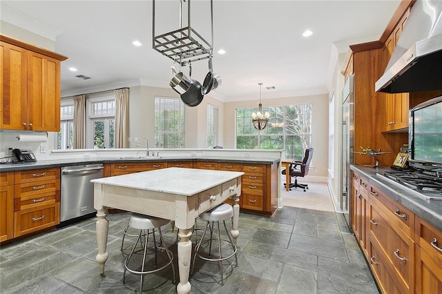 kitchen featuring tasteful backsplash, dark tile flooring, wall chimney exhaust hood, appliances with stainless steel finishes, and an inviting chandelier