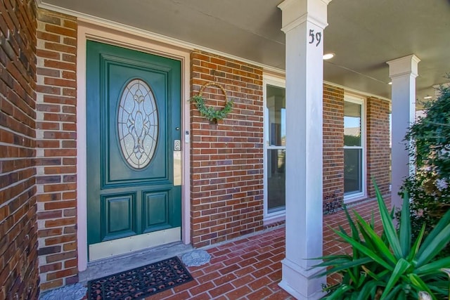 view of exterior entry with covered porch and brick siding