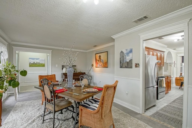 dining room with crown molding, a textured ceiling, and light tile floors