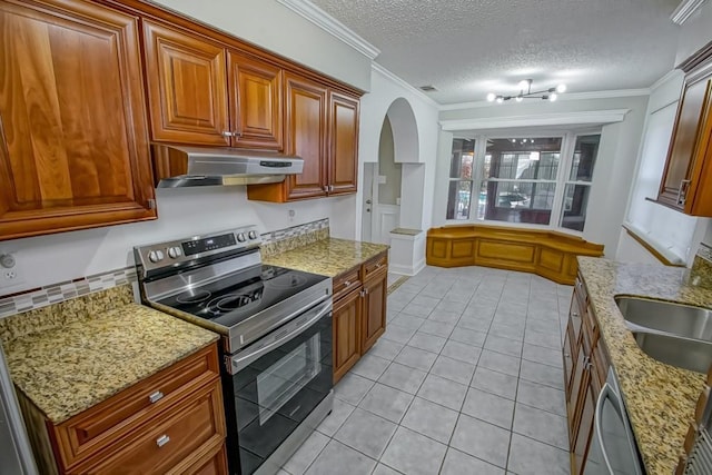 kitchen featuring arched walkways, stainless steel appliances, ornamental molding, a sink, and under cabinet range hood