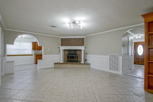 unfurnished living room with arched walkways, ornamental molding, a fireplace, and visible vents