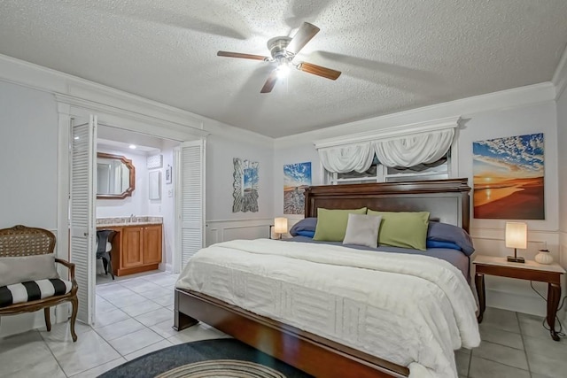 bedroom with light tile patterned floors, ceiling fan, a textured ceiling, and a decorative wall