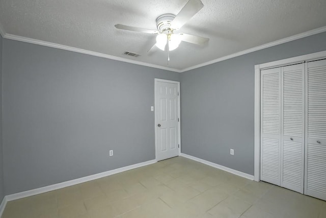 unfurnished bedroom featuring baseboards, visible vents, ornamental molding, a textured ceiling, and a closet