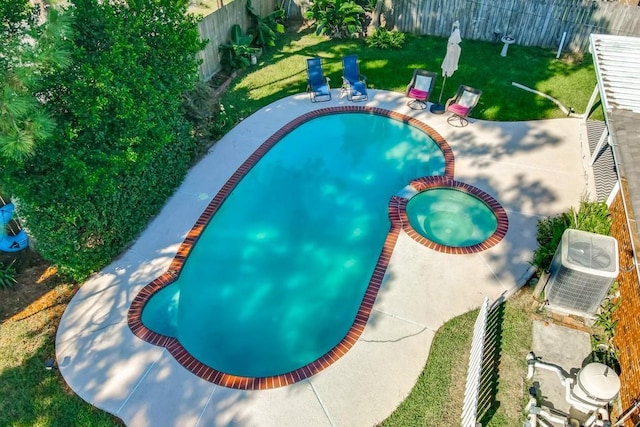 view of pool featuring a lawn, a fenced backyard, a patio area, a pool with connected hot tub, and central AC