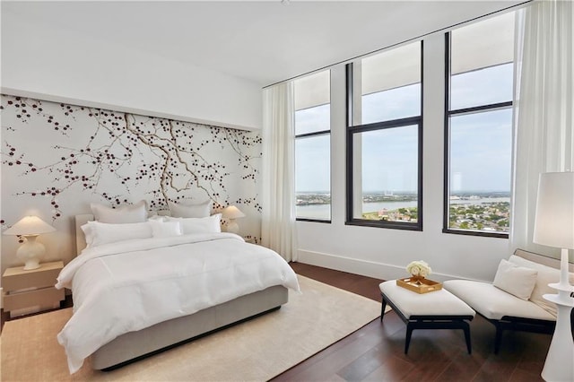 bedroom featuring hardwood / wood-style flooring and a water view