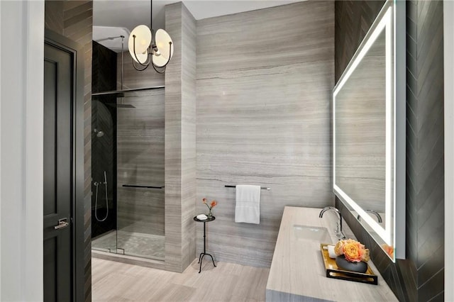 bathroom featuring vanity, tile walls, an inviting chandelier, and walk in shower