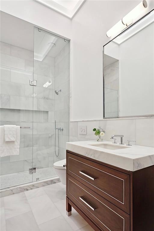 bathroom featuring vanity, toilet, and an enclosed shower