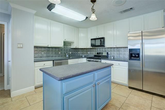 kitchen featuring light tile floors, appliances with stainless steel finishes, white cabinetry, and pendant lighting