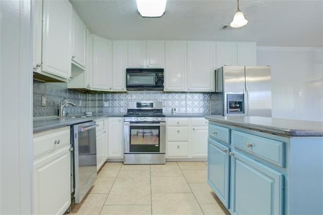 kitchen with light tile flooring, stainless steel appliances, white cabinets, blue cabinetry, and pendant lighting