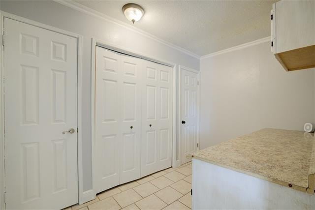 kitchen with ornamental molding and light tile floors