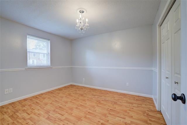 empty room featuring a chandelier and light hardwood / wood-style floors