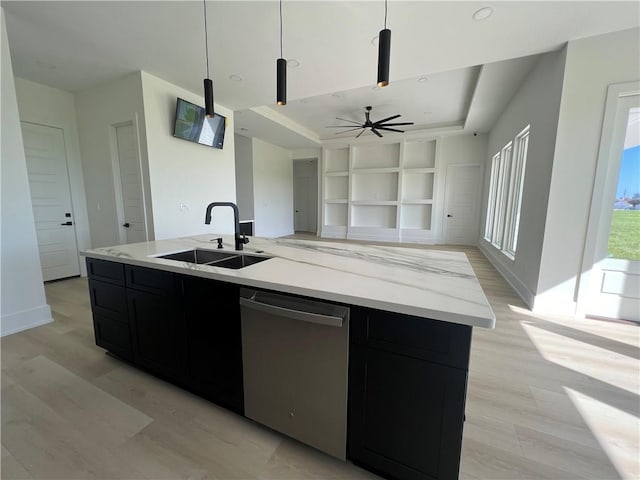 kitchen featuring sink, stainless steel dishwasher, light hardwood / wood-style floors, decorative light fixtures, and a center island with sink