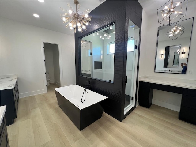 bathroom with hardwood / wood-style flooring, a notable chandelier, vanity, and independent shower and bath