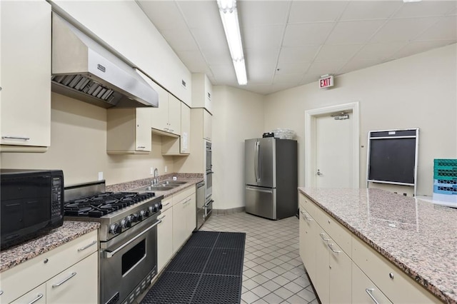 kitchen with light tile patterned floors, sink, extractor fan, stainless steel appliances, and light stone countertops