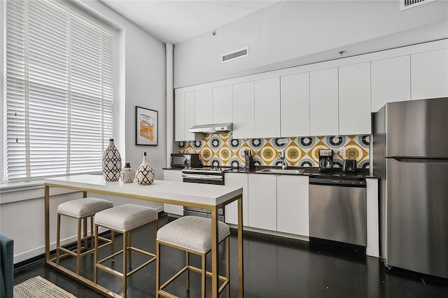 kitchen with sink, a kitchen breakfast bar, white cabinets, stainless steel appliances, and tasteful backsplash