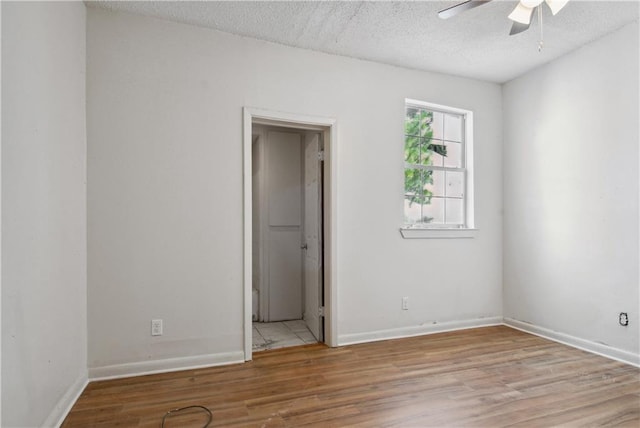 spare room with a textured ceiling, light hardwood / wood-style floors, and ceiling fan