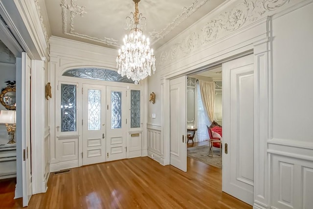 foyer entrance featuring a notable chandelier, ornamental molding, and hardwood / wood-style flooring