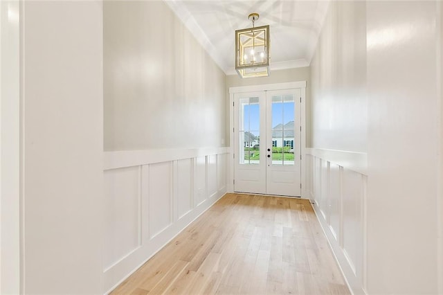 doorway featuring light wood-type flooring, french doors, an inviting chandelier, and crown molding