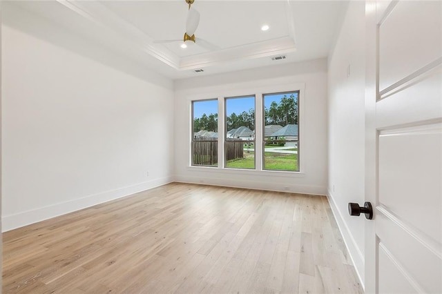 spare room featuring light hardwood / wood-style flooring, ceiling fan, and a raised ceiling