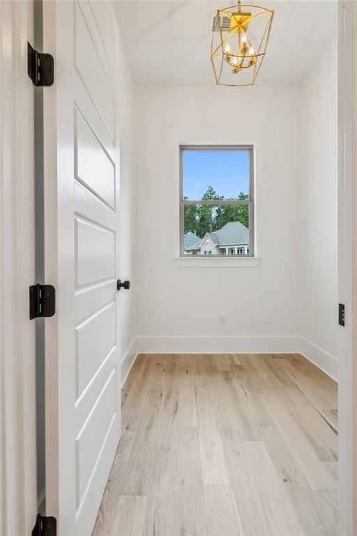 empty room featuring a chandelier and light hardwood / wood-style flooring