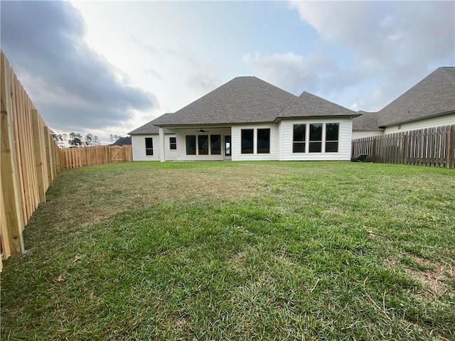 rear view of house with ceiling fan and a yard