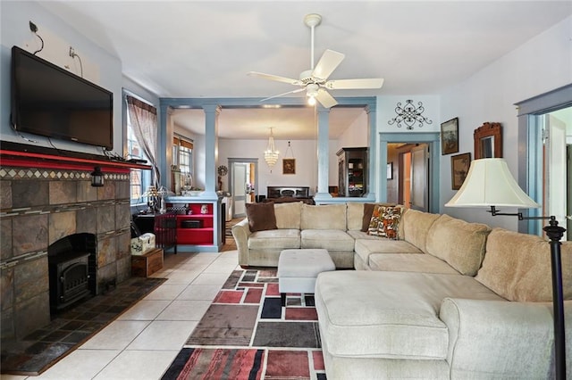 living room with ceiling fan, ornate columns, light tile floors, and a stone fireplace