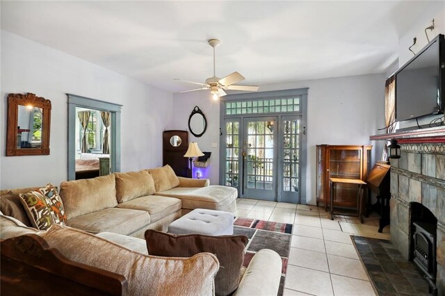 tiled living room with french doors, a tiled fireplace, ceiling fan, and a wealth of natural light