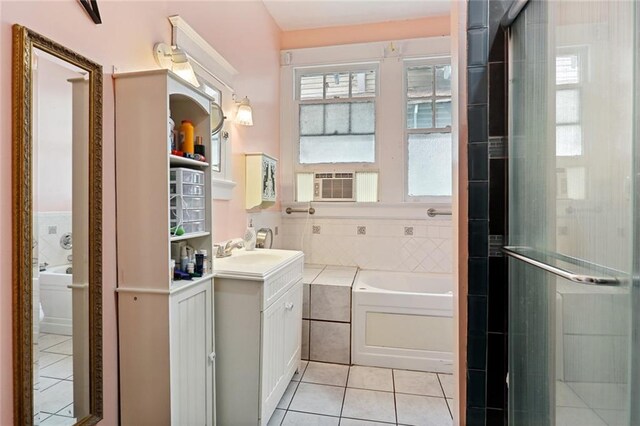 bathroom featuring tiled bath, oversized vanity, tile floors, and a healthy amount of sunlight