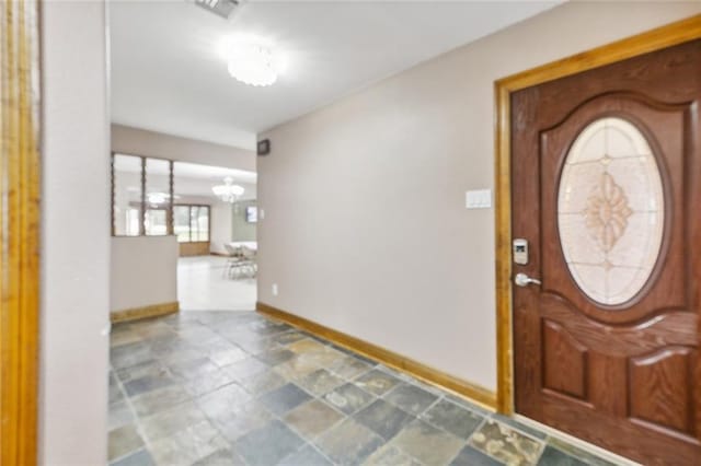 tiled entryway with a chandelier