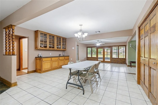 tiled dining space with ceiling fan with notable chandelier