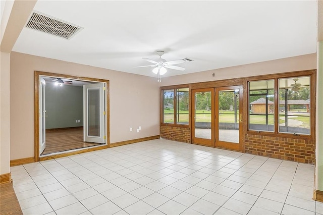 empty room featuring light tile floors, french doors, and ceiling fan