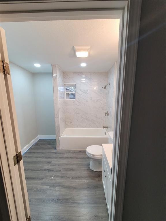 full bathroom with hardwood / wood-style flooring, vanity, toilet, and tiled shower / bath