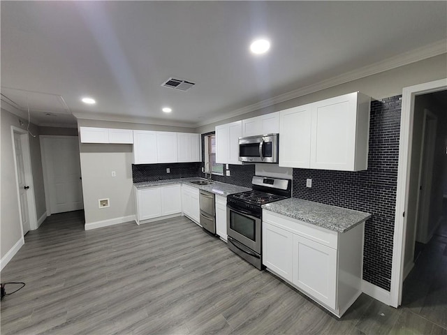 kitchen featuring hardwood / wood-style flooring, appliances with stainless steel finishes, and white cabinetry