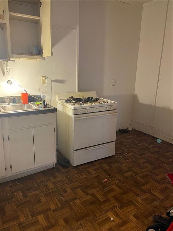 kitchen with dark parquet floors, white cabinetry, and gas range gas stove