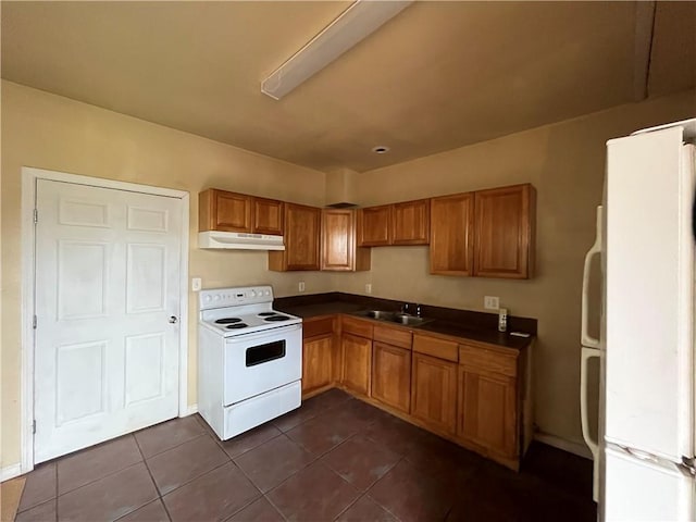 kitchen with white appliances, dark tile flooring, and sink