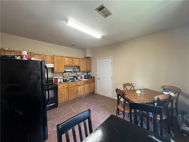 kitchen with light tile floors, black appliances, and sink