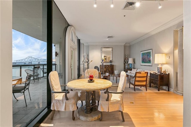 dining space featuring track lighting, ornamental molding, and hardwood / wood-style floors