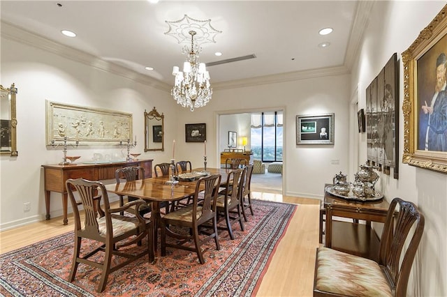 dining space with light wood-type flooring, crown molding, and a chandelier