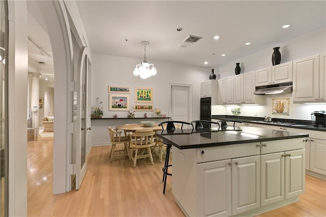 kitchen with pendant lighting, white cabinets, light hardwood / wood-style floors, and a kitchen island