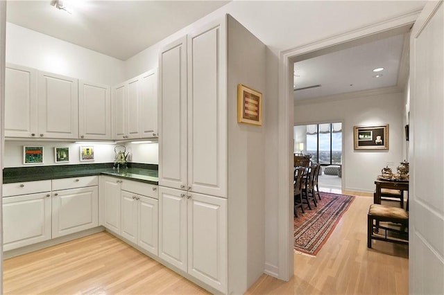 kitchen with light hardwood / wood-style floors, ornamental molding, and white cabinetry