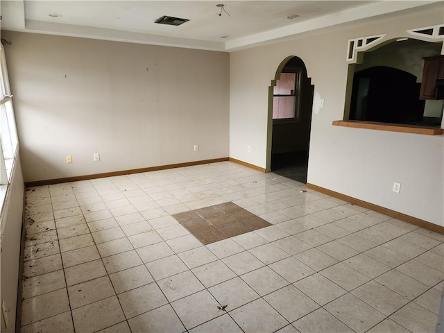 unfurnished room with light tile floors and a raised ceiling