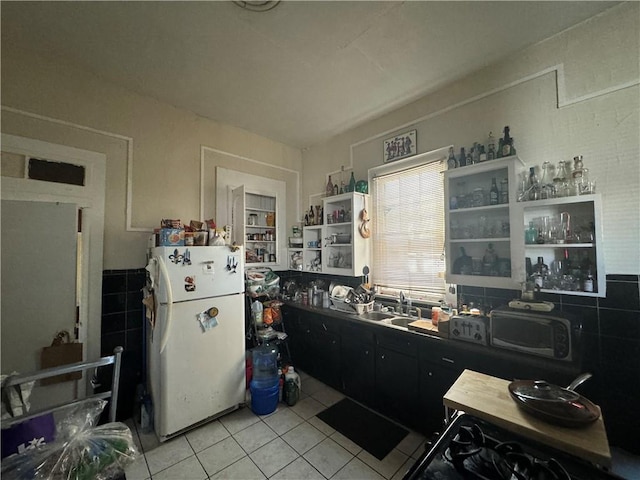 kitchen with white fridge, light tile flooring, and sink