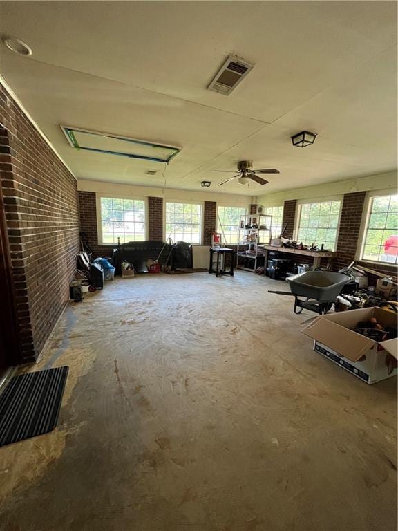 misc room with brick wall, plenty of natural light, and ceiling fan