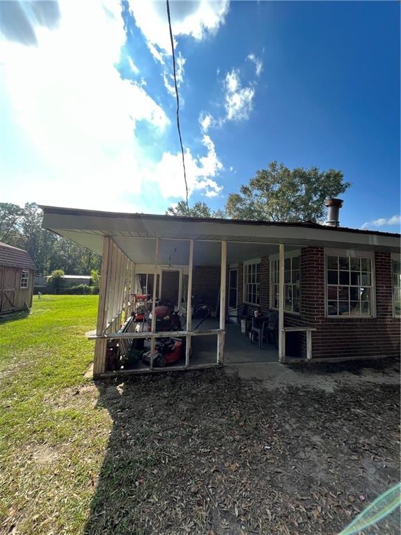 rear view of property featuring a lawn, a patio area, and a storage unit