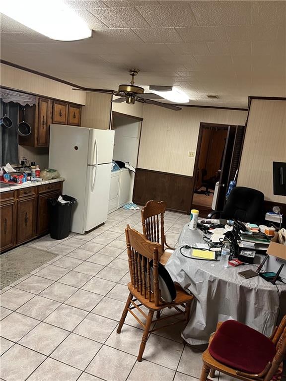 dining room featuring ceiling fan, light tile patterned flooring, washer and dryer, and wood walls