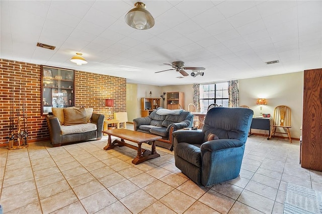 living room featuring ceiling fan, brick wall, and light tile floors