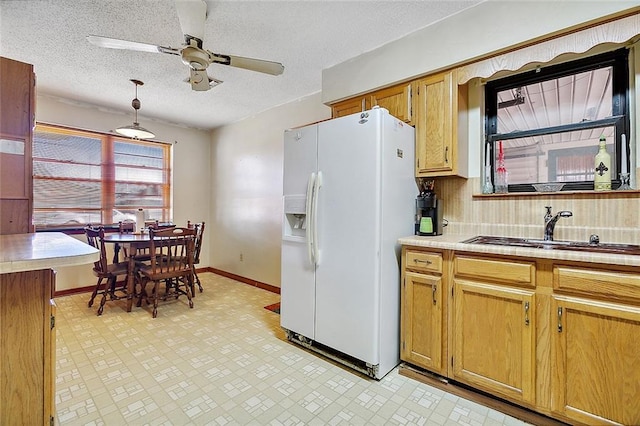 kitchen featuring pendant lighting, ceiling fan, sink, white fridge with ice dispenser, and tasteful backsplash