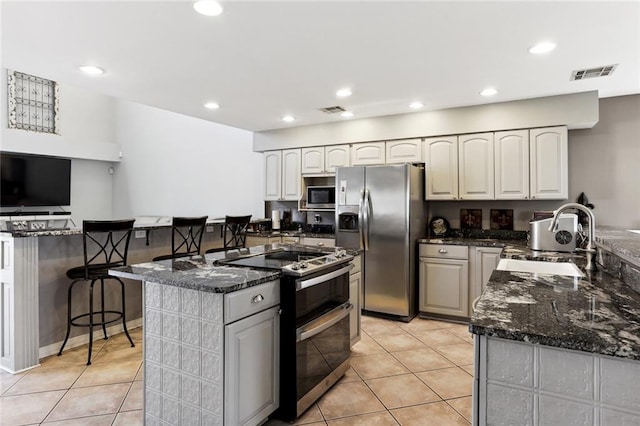 kitchen featuring a breakfast bar, stainless steel appliances, light tile patterned floors, and sink