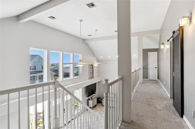 hall featuring vaulted ceiling with beams, light colored carpet, and a barn door