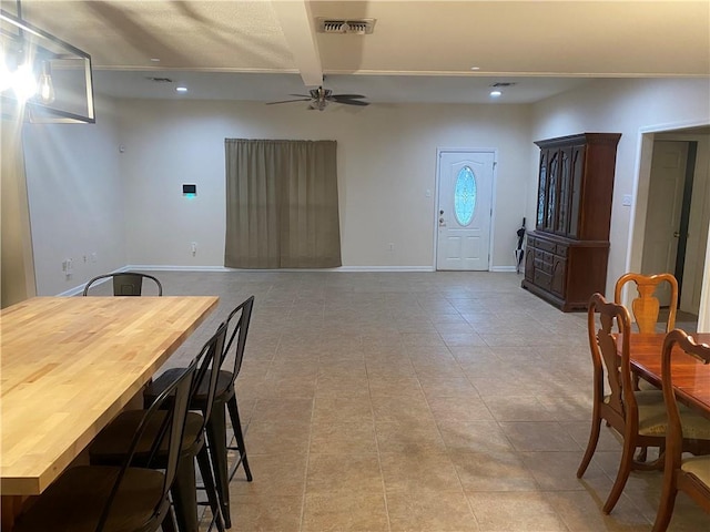 tiled dining space with ceiling fan and beamed ceiling